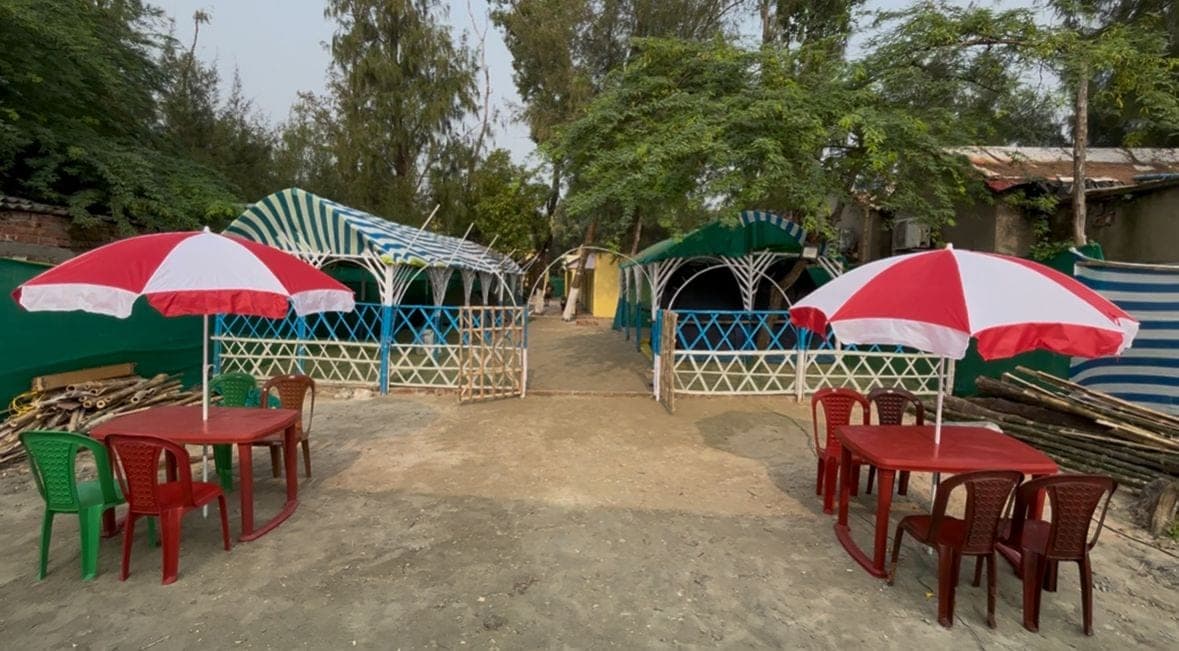 Red and white umbrellas and tables in the sand outside the camp gazebos